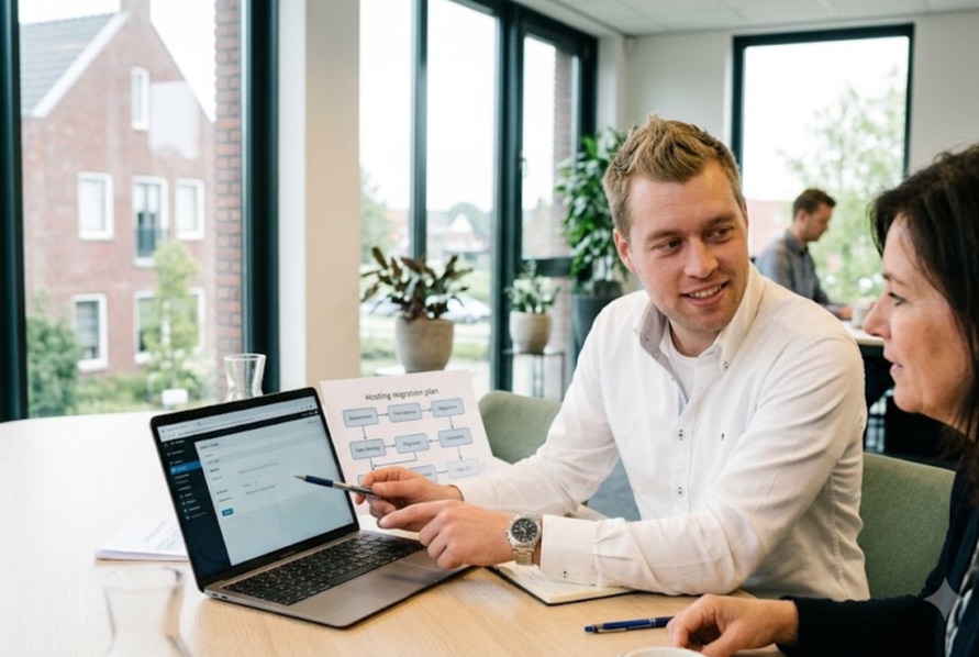 Engineer van Hostingway legt een klant het migratieplan uit op een laptop
